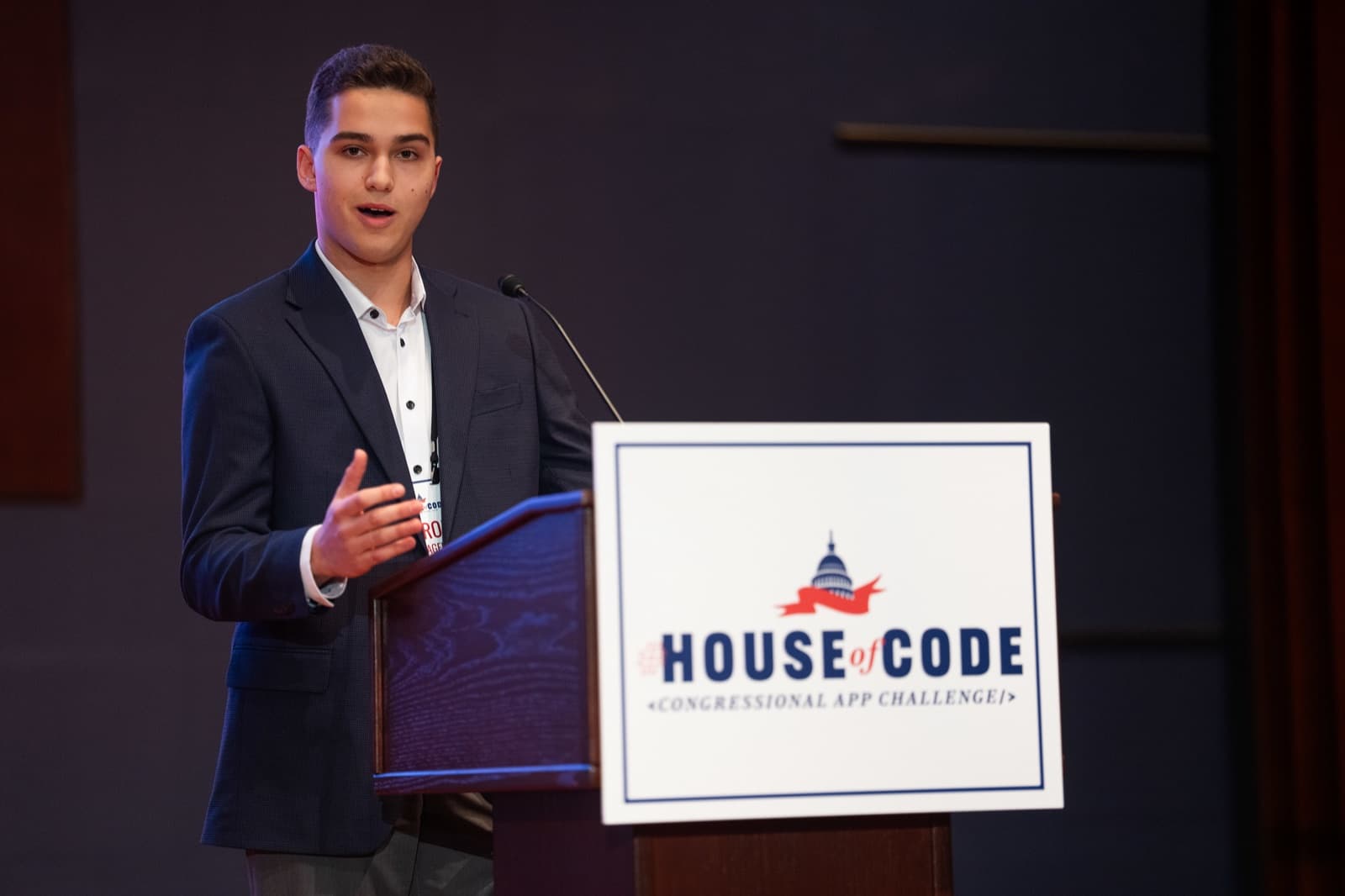 Aaron Prager speaking at a podium with a House of Code, Congressional App Challenge sign